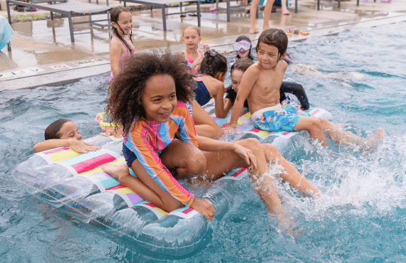 A bunch of children playing on a floatie in the pool