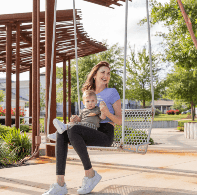 Woman smiling on a bench with a baby in her lap